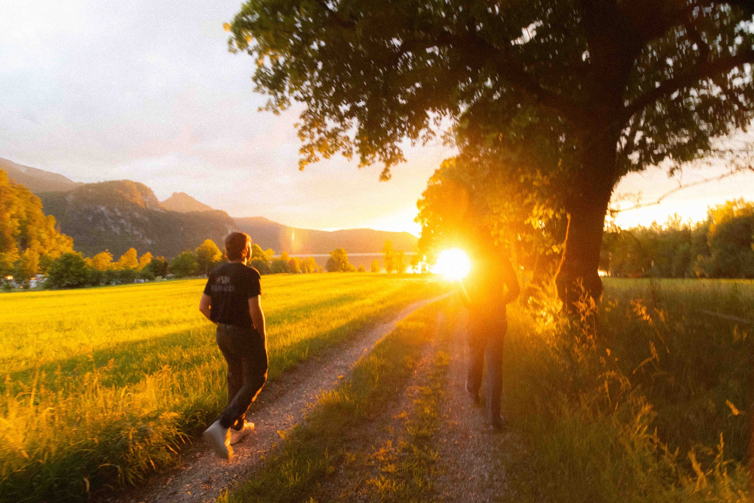 Two friends walking toward the sunset on a mountain path